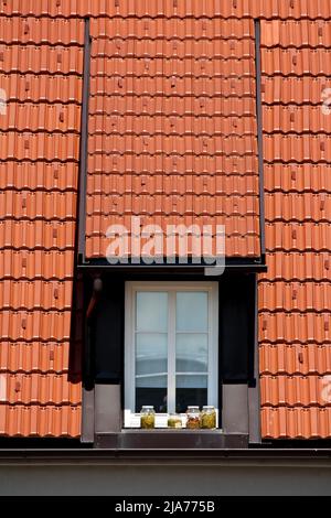 Shiny new metal flue pipe with wide cover on top held by four narrow metal strips next to stained family house wall with dirty smoke chimney stains Stock Photo