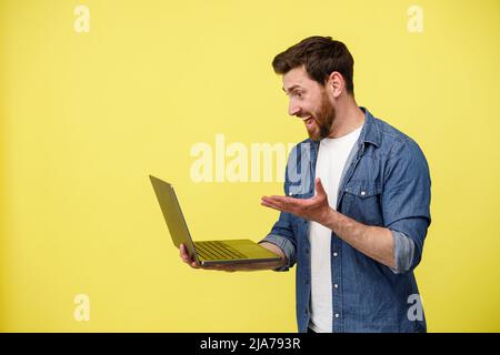 Emotional man holding laptop and talking by video call actively gesturing Stock Photo