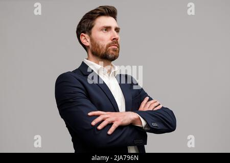 Serious business man in classic black suit with crossed hands looking at side  Stock Photo