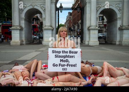 London, England, UK. 28th May, 2022. PETA supporters wearing little more than bear masks and lying on 'blood''-soaked Union Jack flags will held a bloody 'die-in'' at Marble Arch to protest the UK Ministry of Defence's (MoD) support of the slaughter of Canadian black bears, whose fur is used to make the caps worn by the Queen's Guard. (Credit Image: © Tayfun Salci/ZUMA Press Wire) Stock Photo