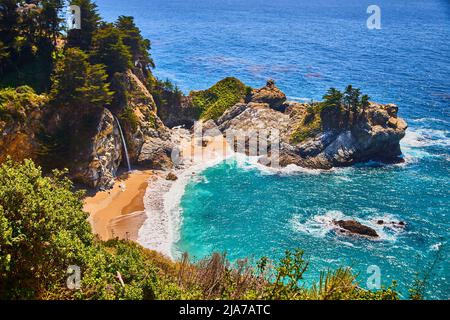 Hidden ocean cove leads to beautiful waterfall on sandy beaches Stock Photo