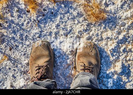 Boots standing in white powdered sand desert with yellow grasses Stock Photo