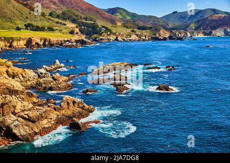 Boulders and rocky coast meet ocean waves on west coast Stock Photo