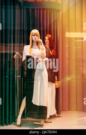 Female mannequin in shop window showcase of store mall market. Fashion clothes - dress, jacket. Mannequins dressed in female woman fashion clothes in Stock Photo