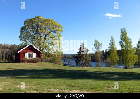 DALARNA, SWEDEN ON MAY 16, 2022. View of a red wooden building, park in the Swedish landscape. Editorial use. Stock Photo