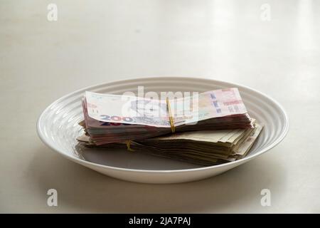 Ukrainian one hundred and two hundred hryvnia lie on a plate on the table in the kitchen,hryvnia,finance and economy Stock Photo