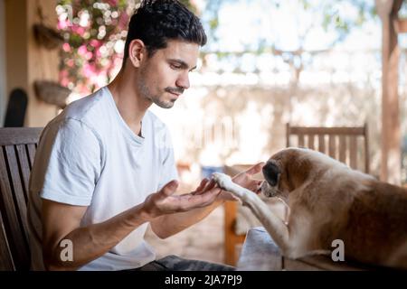 a young man plays with his dog in the garden Stock Photo