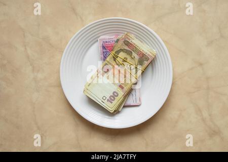 Ukrainian one hundred and two hundred hryvnia lie on a plate on the table in the kitchen,hryvnia,finance and economy Stock Photo