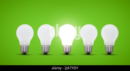 Five light bulbs in a row, center light bulb is brightly lit. Green background. Idea concept. Stock Photo