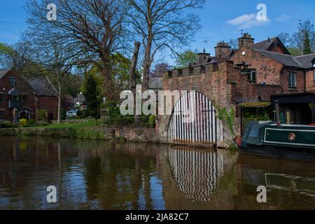 Traditional scene of the bridge water canal and barge, with the stripy gate reflecting in the water in Worsley, Manchester, United Kingdom. Stock Photo