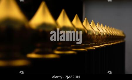 Golden metal bulbs on a fence receding in a row with shallow depth of field Stock Photo