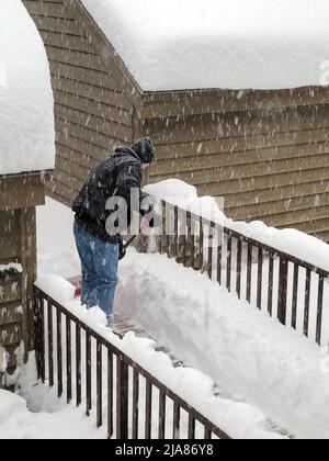 Senior man shoveling snow on a deck walkway Stock Photo