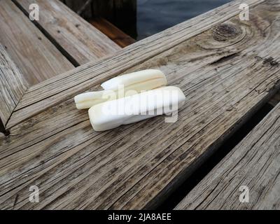Slivers remaining from a bar of soap sitting on the worn wood of an old dock Stock Photo