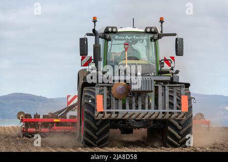 A Front View of a Farmer in a Fendt Tractor Pulling a Disc Seed Drill in a Field in Spring