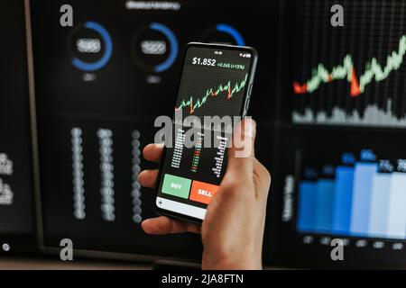Financial trader man investor using mobile phone app to analyze stock market Stock Photo