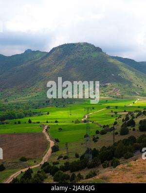 Vertical view of winding dirt country road with mountains in the background. Stock Photo