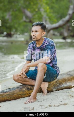 Asian man sitting on wooden in beach Stock Photo