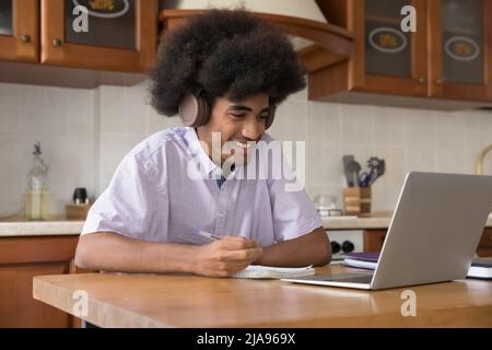 Joyful African high school student guy wearing wireless headphones Stock Photo