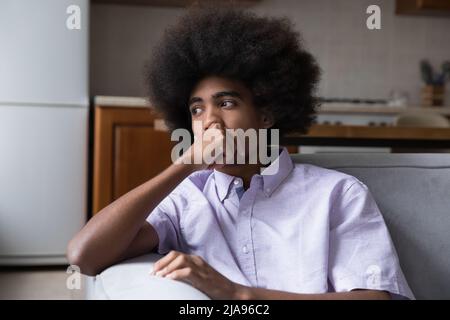 Pensive frustrated teenage African guy sitting on couch Stock Photo