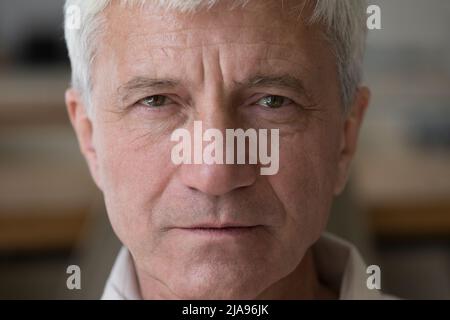 Serious wrinkled hoary senior man grandfather retiree looking at camera Stock Photo