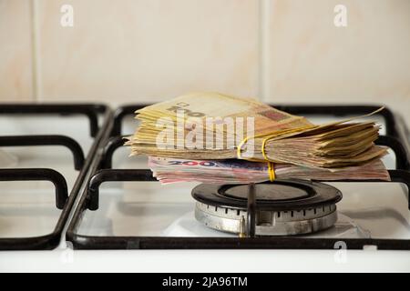 One hundred and two hundred hryvnia lie on a gas stove in the kitchen, Ukrainian hryvnia and gas, finance and economics, money and sanctions Stock Photo