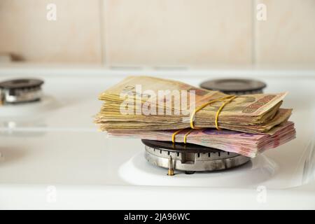 One hundred and two hundred hryvnia lie on a gas stove in the kitchen, Ukrainian hryvnia and gas, finance and economics, money and sanctions Stock Photo