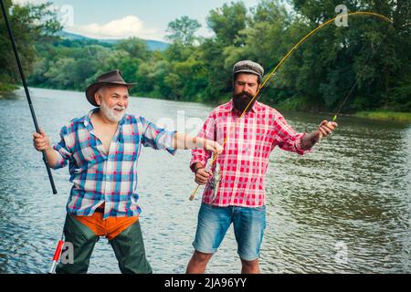 Two friends catching fish with fishing net and rod sitting on the