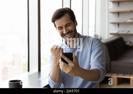Happy excited businessman looking at smartphone screen Stock Photo