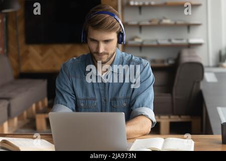 Focused student in wireless headphones listening to online learning seminar Stock Photo