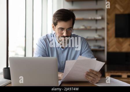 Focused businessman reviewing paper reports, received letter Stock Photo