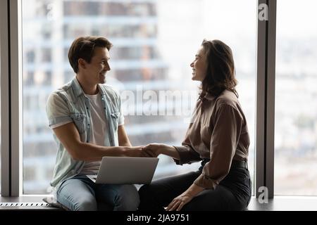 Happy customer shaking hands with professional with laptop Stock Photo