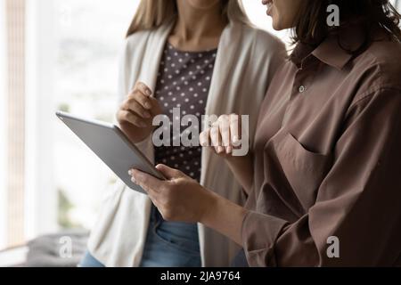 Female business coworkers using tablet together, watching virtual online presentation Stock Photo