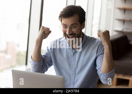 Happy surprised businessman excited with good news, using laptop Stock Photo
