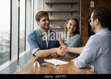 Happy couple of customers and real estate agent shaking hands Stock Photo