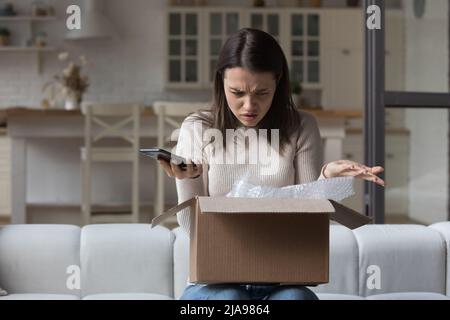 Puzzled dissatisfied customer getting damaged good from Internet store Stock Photo