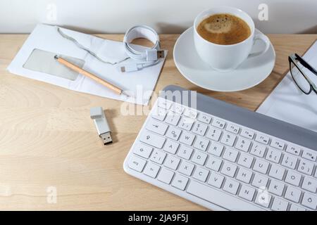 Computer keyboard, coffee, usb stick and papers on a wooden office desk for business at home, copy space, selected focus, narrow depth of field Stock Photo