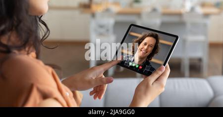 Young brunette woman using tablet computer to call boyfriend Stock Photo