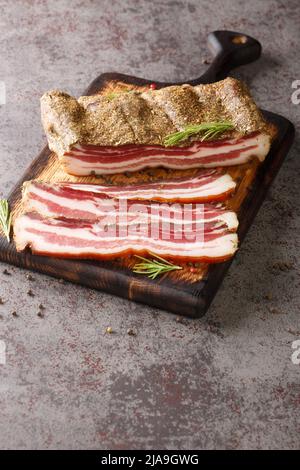Dry cured pork belly, smoked pork meat delicacy food closeup on the wooden board on the table. Vertical Stock Photo