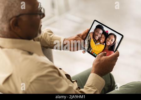 Senior black man calling his family, using digital tablet Stock Photo