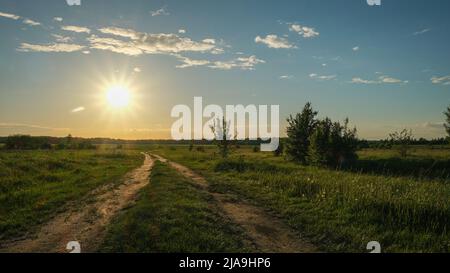 Landscape of a field road and the sun at sunset. Stock Photo