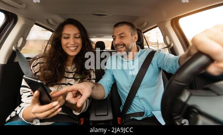 Happy couple driving car and using cell phone Stock Photo