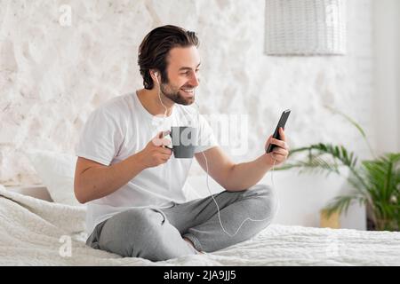 Smiling guy having video chat with friends in the morning Stock Photo