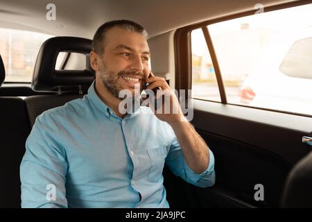 Businessman talking on smartphone while going by car Stock Photo