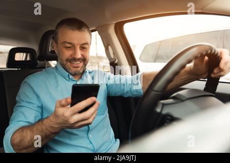 Happy man using smartphone while driving car Stock Photo