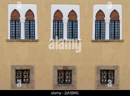 Wooden antique windows with arched shape on a painted old wall. Stock Photo