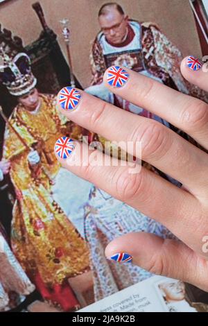 Woman with fingernails painted with the British flag resting on OK magazine with a picture from the Queen's Coronation. Platinum Jubilee June 2022 Stock Photo