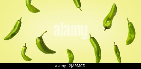 Creative banner with green peppers flying on light yellow background. Long food banner with copy space. Stock Photo