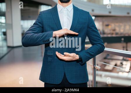 Cropped millennial muslim businessman in suit hold empty space in his hands in office interior, close up Stock Photo