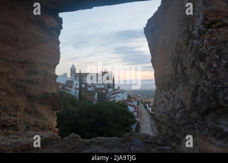 Monsaraz, Alentejo, Portugal. View from an opening in the wall of the castle on the Parochial Church of Nossa Senhora da Lagoa at dawn. Stock Photo