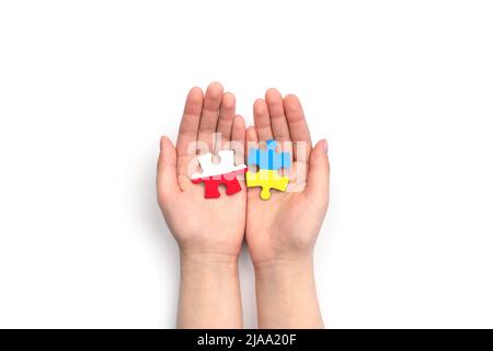 Hands hold two puzzles with flags of Poland and Ukraine on white background. Unity solidarity partnership help concept Stock Photo